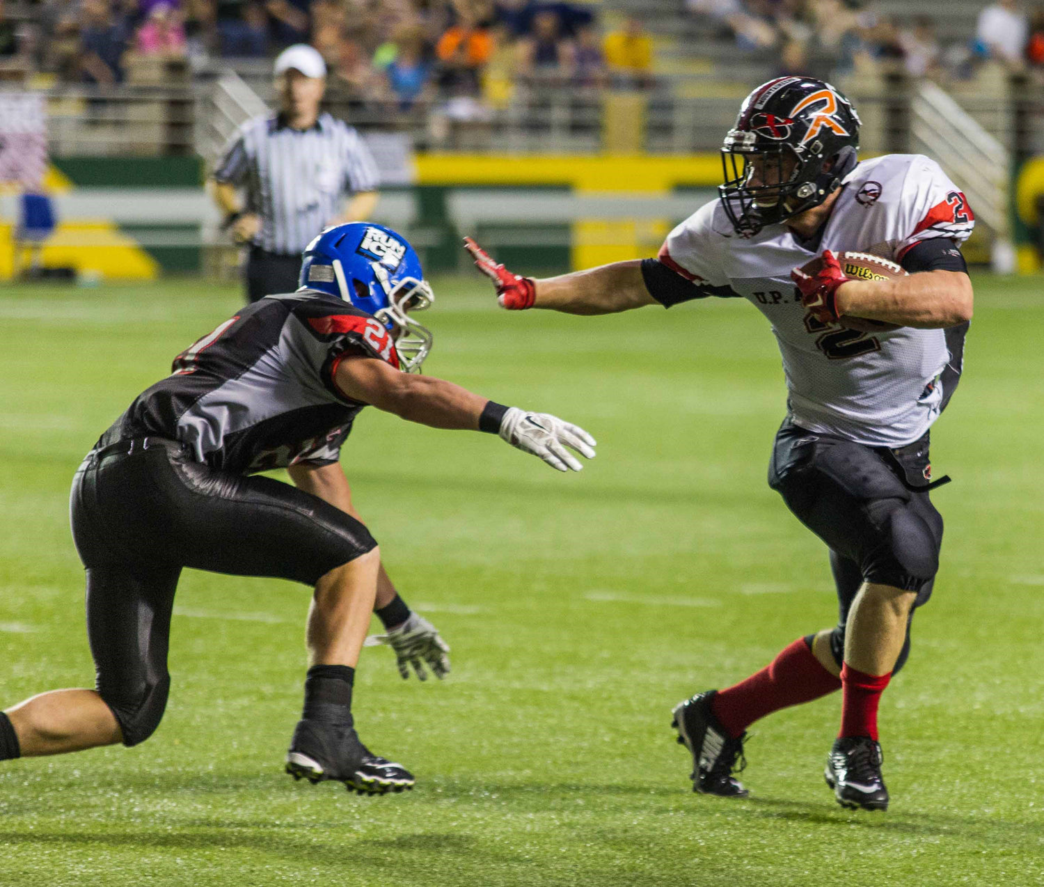 football player running with the ball while defender tries to tackle