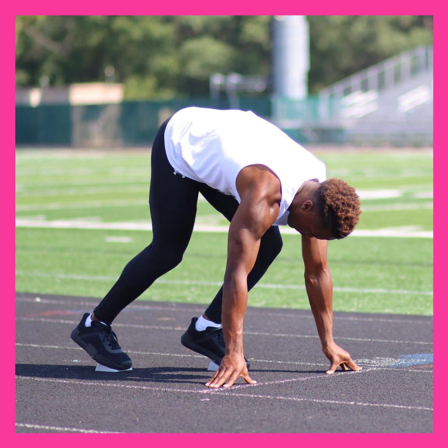 male track runner at the starting line in a 4 point stance