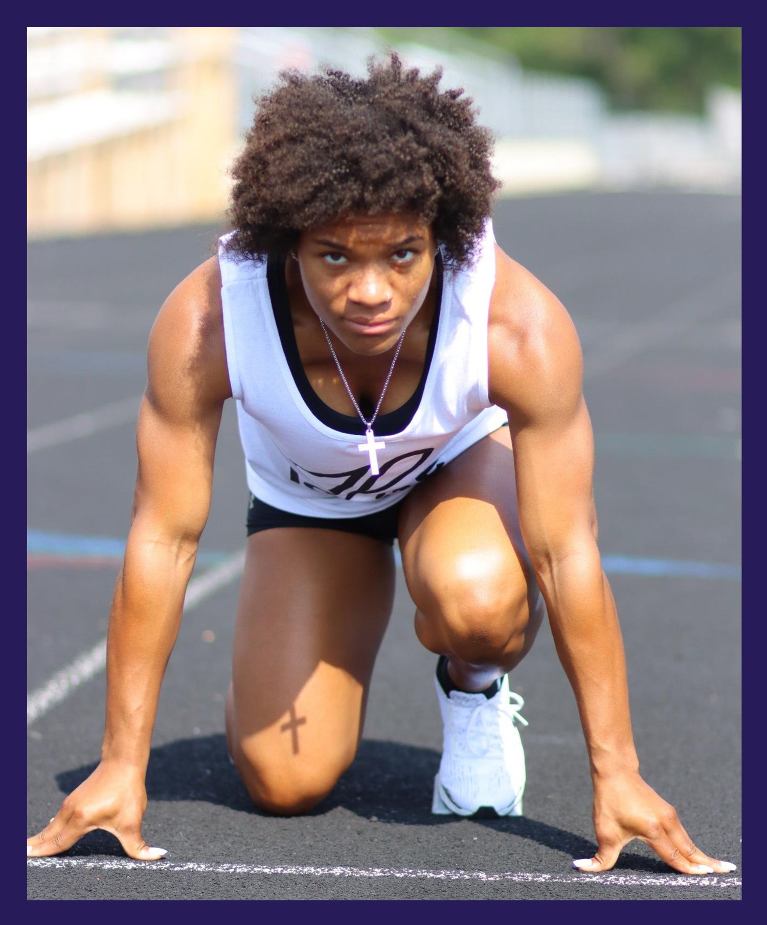 female track runner at the starting line in a 4 point stance