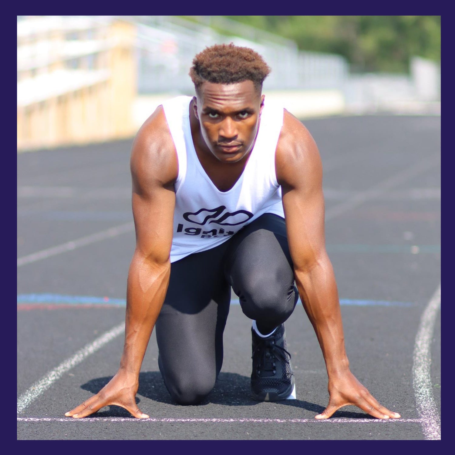 male track runner at the starting line in a 4 point stance