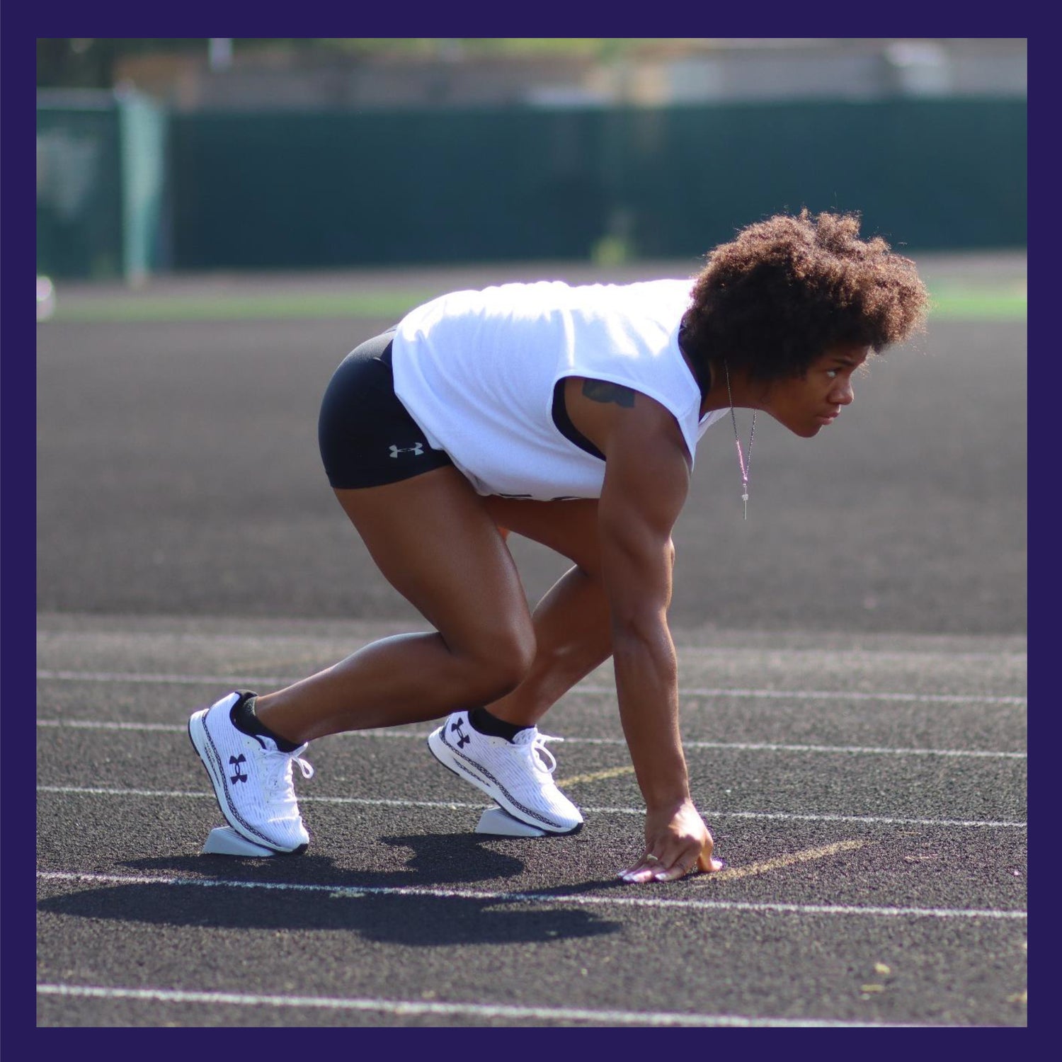 female track runner at the starting line in a 3 point stance