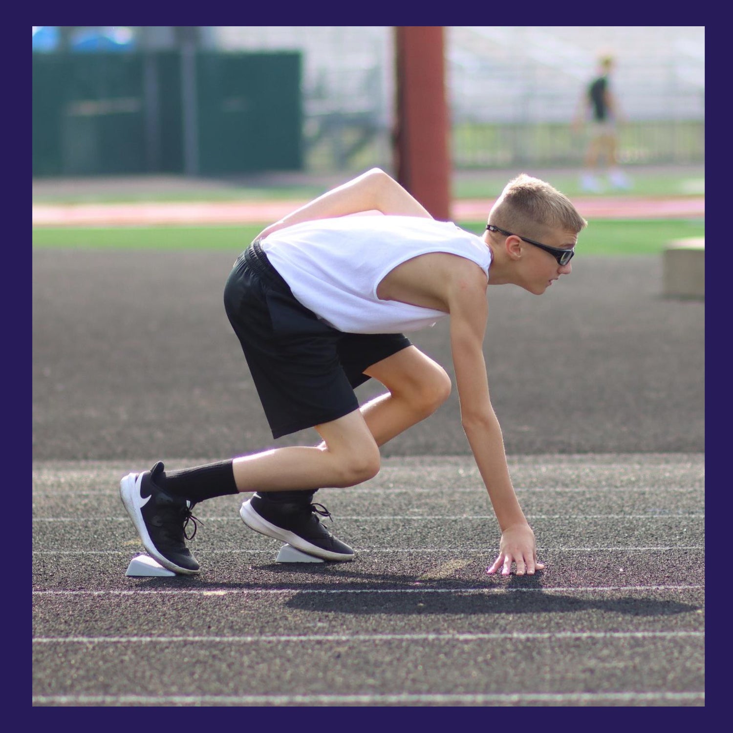 male youth track runner at the starting line in a 3 point stance
