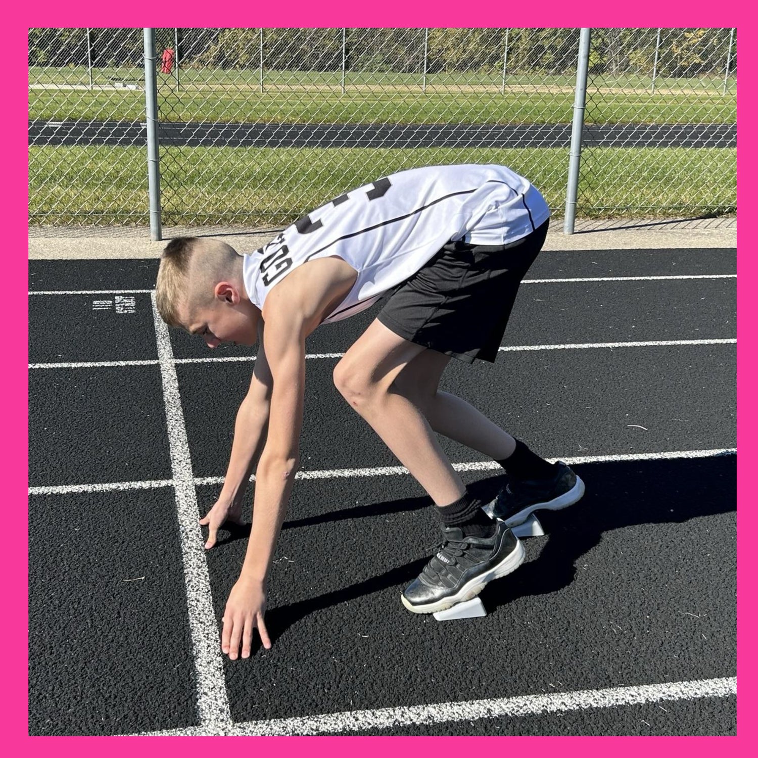 male youth track runner at the starting line in a 4 point stance